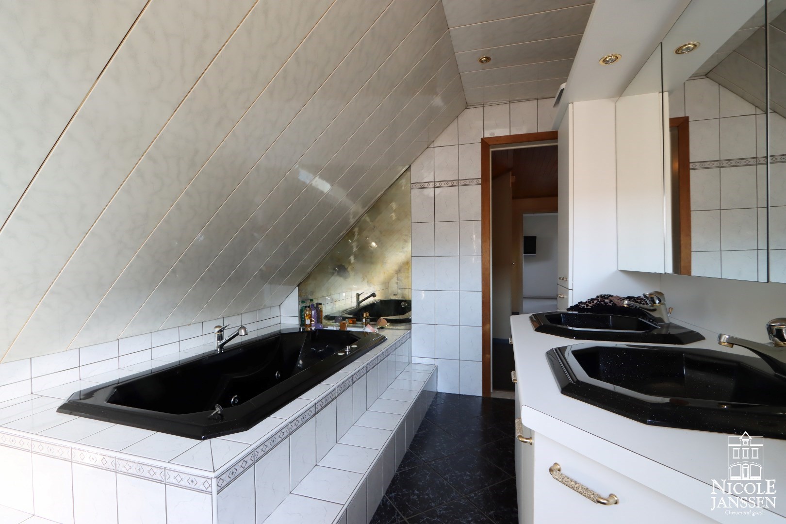 Betegelde badkamer met ligbad en dubbele wastafel