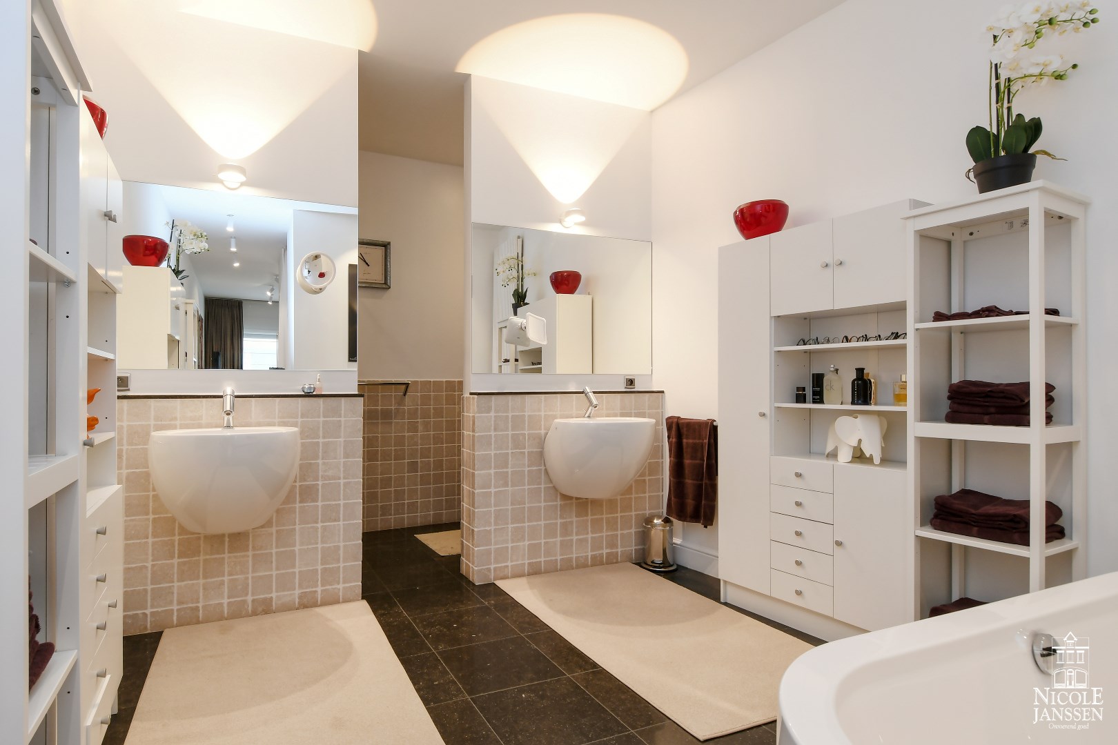 Compleet ingerichte badkamer met ligbad, betegelde douche, toilet en twee wastafels (design porselein Philippe Starck Design)