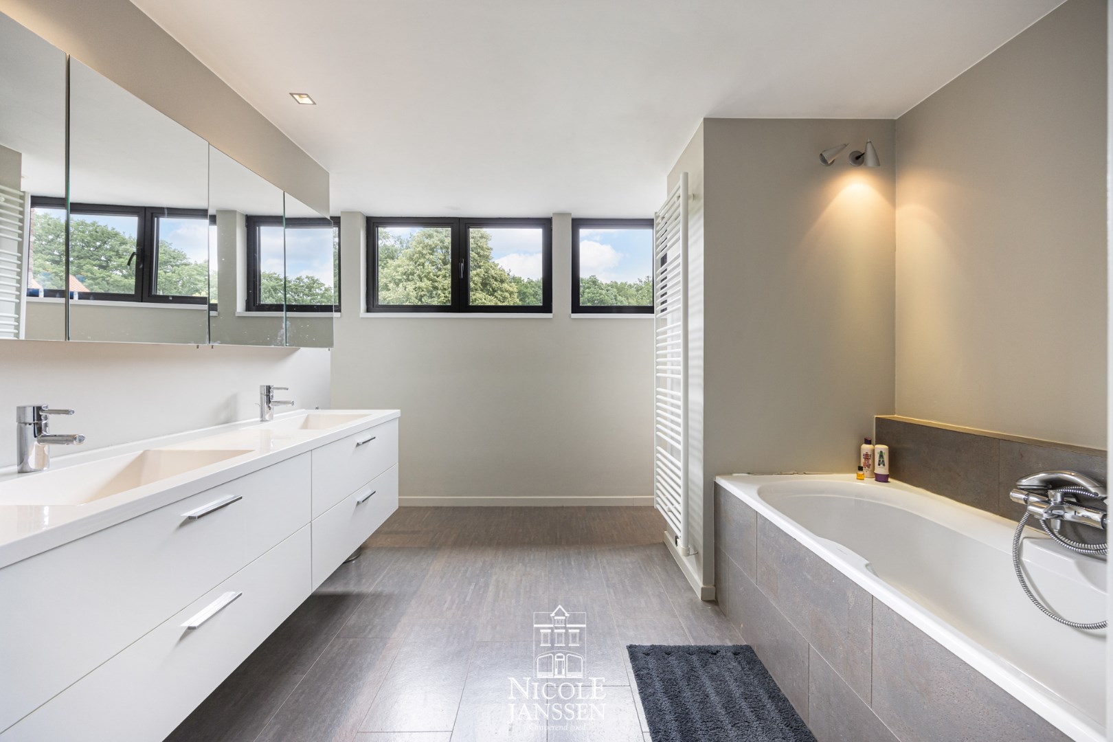 Ensuite badkamer met ligbad, douche en dubbele lavabo in badkamermeubel 